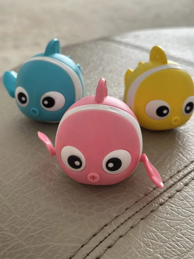 mechaniczne rybki do kąpieli - niebieska, żółta i różowa - na be zowej kanapie